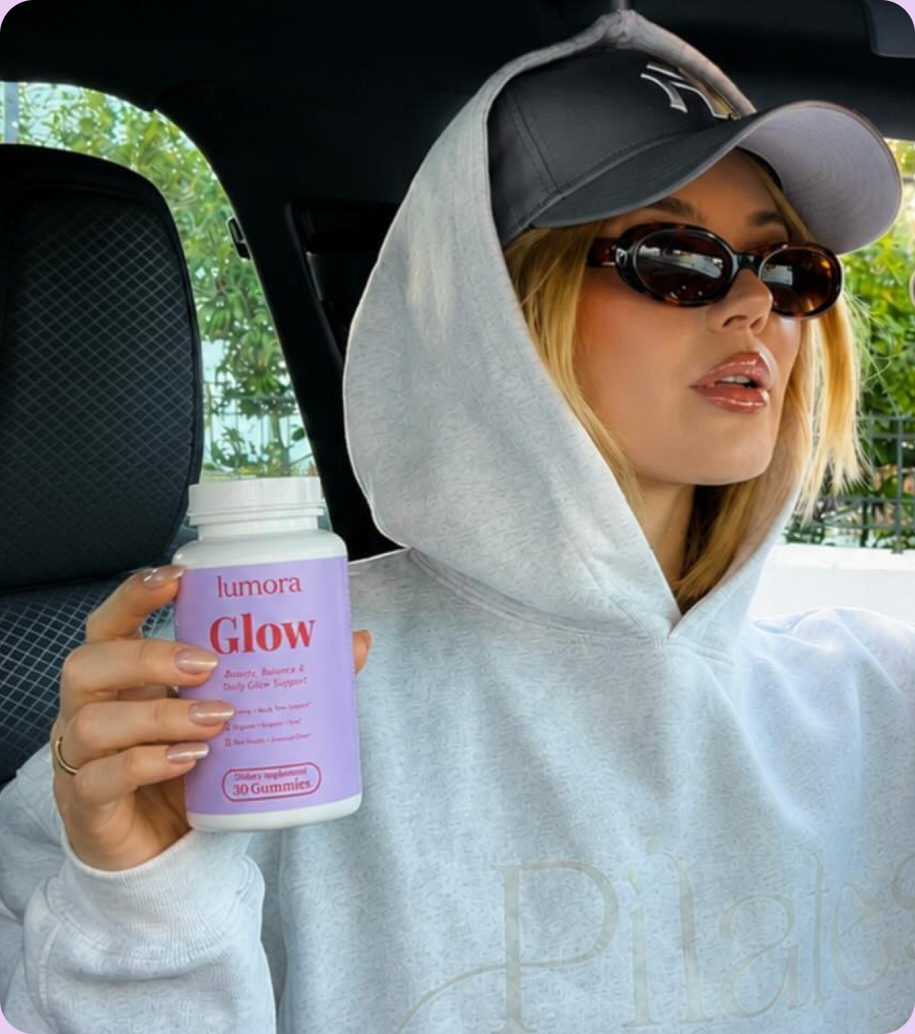 Woman in a car holding a bottle of Lumora Glow